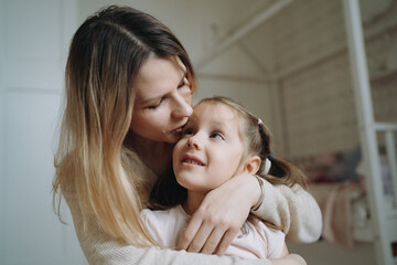 mother hugging and kissing her adorable daugter