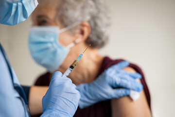Doctor makes vaccination to senior woman with surgical mask - obrazy, fototapety, plakaty