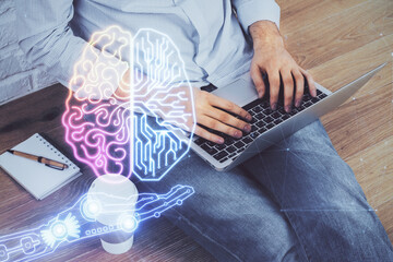 Businessman with computer background with brain theme hologram. Concept of brainstorm. Multi...