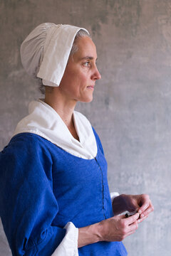 Vertical Medium Side View Of Woman Dressed In 17th Century Costume Holding A Knife, Quebec City, Quebec, Canada