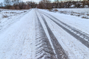 Fototapeta na wymiar Tire tracks on icy road covered with snow