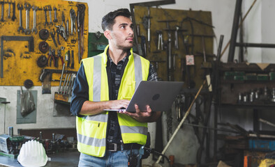 A factory engineer holding a laptop and looking up