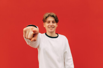 Happy guy shows his finger to the camera on a red background and smiles. Focus on the fingers....