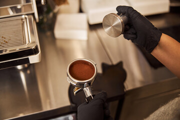 Fototapeta na wymiar Experienced barista making coffee pad while working