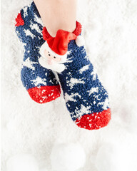 Woman's feet in christmas socks, snowballs, snow as background