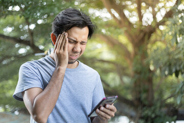 young asian man suffering from severe headache outdoor