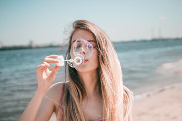girl blowing bubbles on the beach