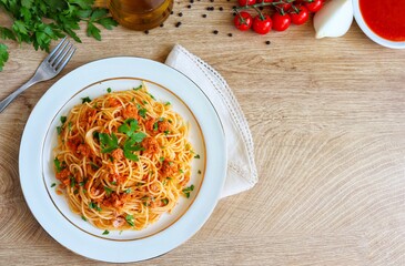 Selective focus on Italian Traditional Pasta"Spaghetti with canned tuna in olive oil", spaghetti with canned tuna,tomato sauce,onion,parsley,olive oil and peppers on plate with wooden table background
