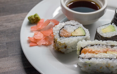 Sushi rolls and sushi sandwiches on white plate with selective focus close up