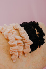 Scrunchy or scrunchies headband fabric texture in black and beige color with pink background isolated.
