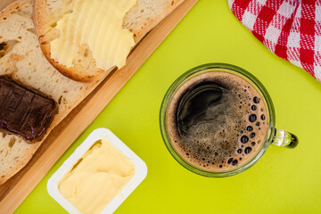 Café con tostadas de mantequilla y mermelada de fresa, sobre un mantel verde, visto desde arriba