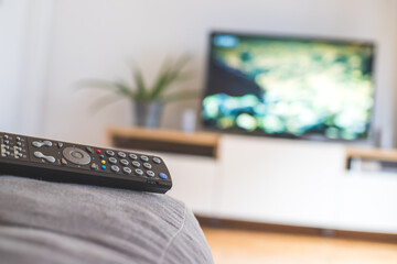 Remote control on the sofa, streaming on a smart TV.