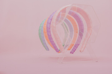 Colored tiaras in acrylic display. Studio photo with pink background