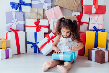 Beautiful little fashionable girl opens gifts for the holiday birthday