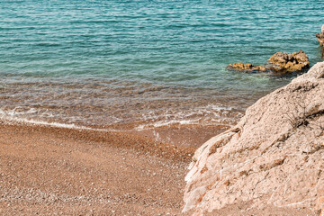 Rocks, blue sea and swash coming onto the gravel beach.