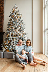 Happy young family of three near Christmas tree