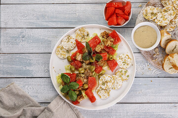 Signature dish. Vegan salad with watermelon, olives, fresh herbs, basil, multi-grain chips and peanut sauce. Healthy and tasty food. Top view