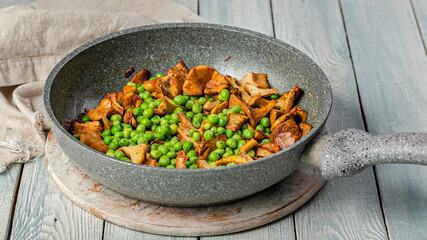Food banner. Fried chanterelles with vegetables in a pan. Edible mushrooms and green peas. Vegeterian food.