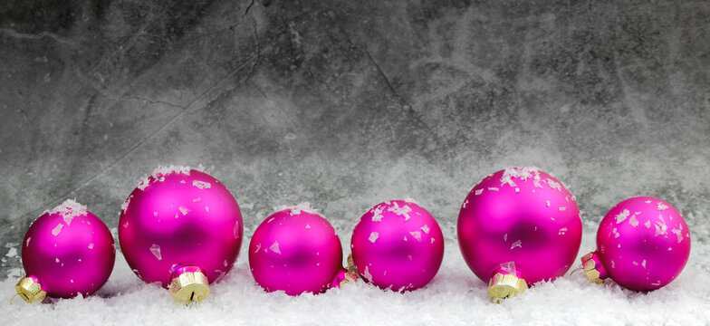 pink christmas balls with snow on grey background 