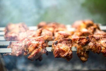 Shashlik or shish kebab preparing on barbecue grill over hot charcoal. Grilled pieces of pork meat on metal skewers.