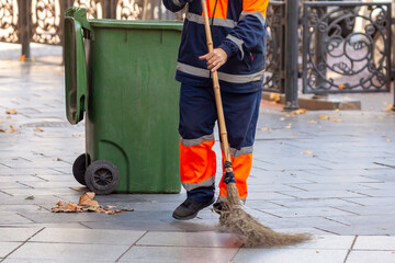 Janitor works in the street with a broom