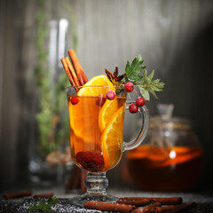 mulled wine tea with cinnamon and orange stands on a dark background	
