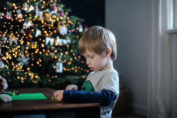 The boy blond plays the constructor near the Christmas tree. Christmas atmosphere, holiday, garland