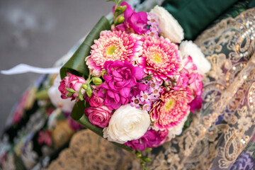Traditional costume from Valencia. Floral pattern. Woman holds a bouquet of pink flowers