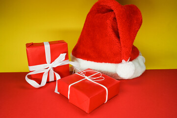 Red santa claus hat and wrapped gift boxes on a colored background. Christmas card concept