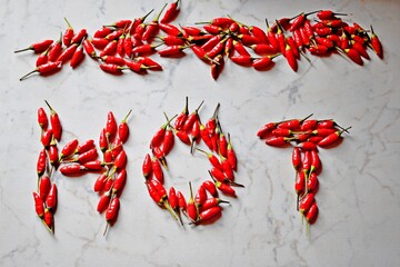 closeup of HOT inscription made with fresh hot peppers on a kitchen table