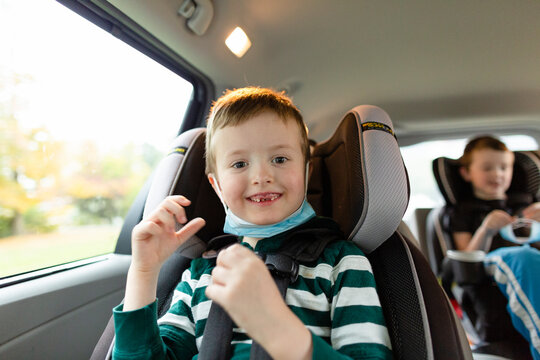 Elementary Age Boy Smiling While Sitting in Car With Face Mask