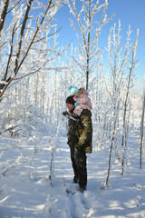 Happy family enjoys walking through the snowy forest, winter fun. Dad and daughter spend time together.