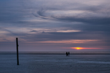 Two people on the beach at sunset