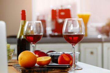 Glass of red wine and oranges on kitchen counter