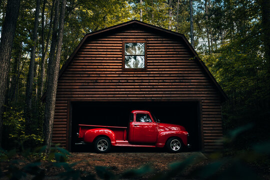 Antique rustic 1950's red truck in a wooden log barn in the woods