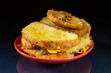 Roasted white bread in milt with egg on red plate
