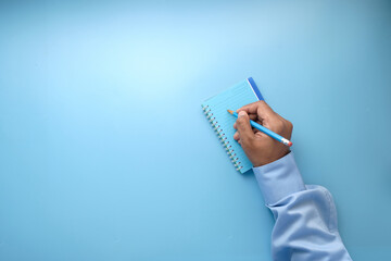 man hand writing on notepad on blue background 