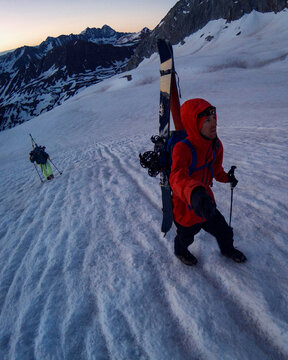 Male and female hikers splitboarding on snowcapped mountain