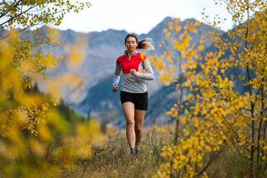 Young woman running in forest during autumn
