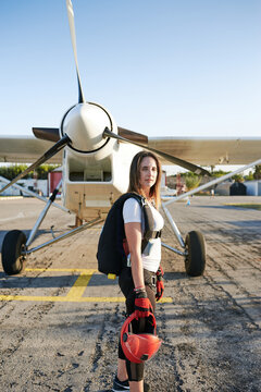 Young female skydiver in an airfield with a plane behind her