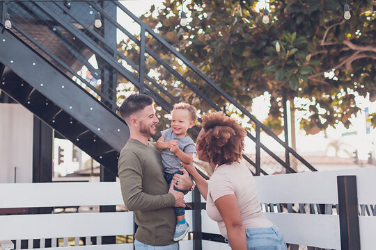 Dad holding baby boy and mom trying to make him laugh
