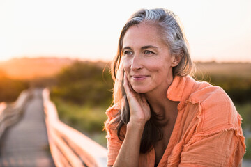Fototapeta premium Portrait of Gray Haired Woman at the beach for sunset