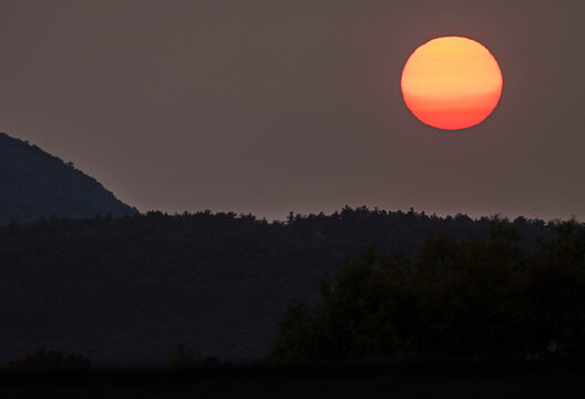 Defused sun colored by western fires sets in Vermont
