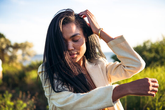 Black Multiracial Woman lifestyle portrait by the ocean at golden hour