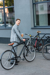 Fototapeta na wymiar Cheerful businessman with takeaway coffee standing near bicycle parking outdoors