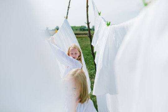 Little blondes hang washed sheets