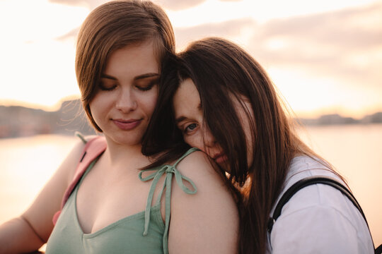 Portrait of happy lesbian couple standing on bridge at sunset