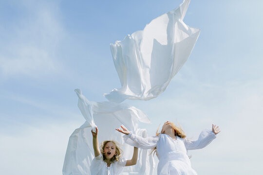 children throw washed sheets into the sky