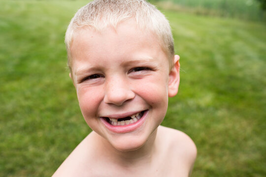 Close Up of Smiling Toothless Young Boy With a Buzz Cut in Backyard