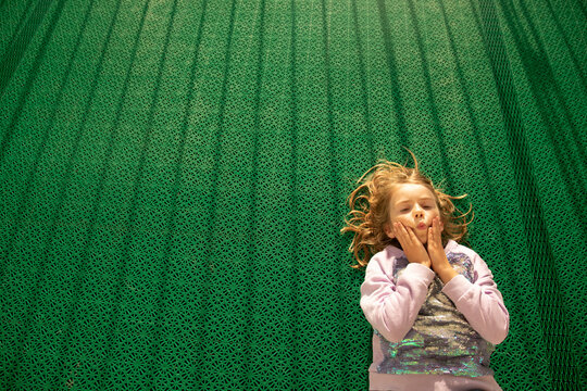 Girl Laying on Green Floor With Funny Expression in Helsinki, Finland